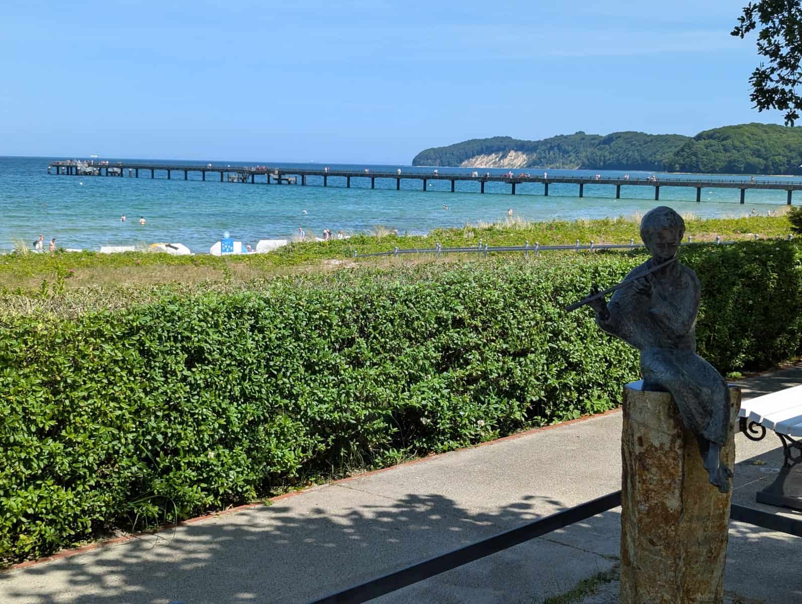 Bronzestatue am Strand von Binz mit Seebrücke und Ostsee im Hintergrund