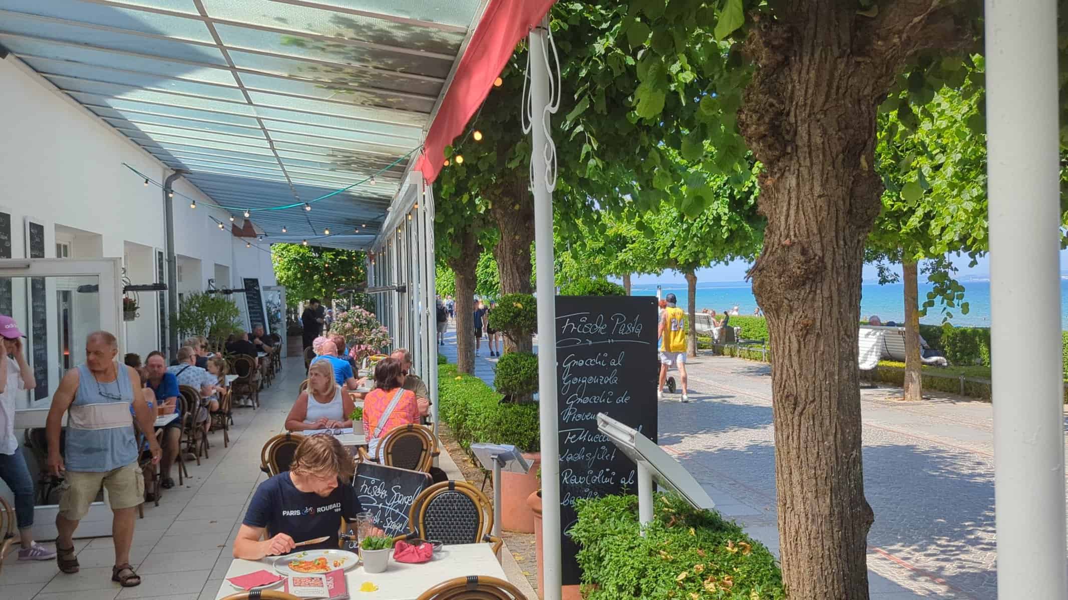 Strandrestaurant in Binz mit Gästen unter Sonnenschirmen und Blick auf die Ostsee