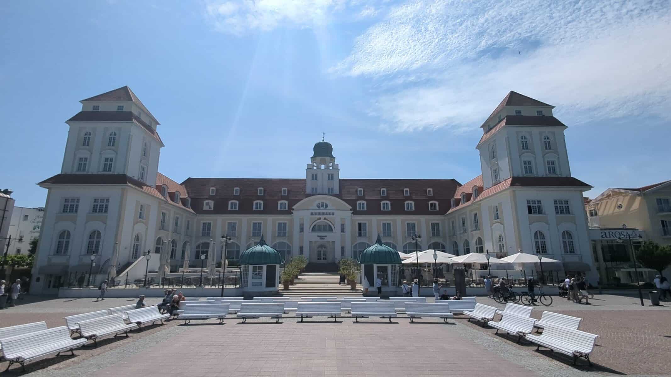 Kurhaus Binz in Weitwinkelansicht mit Platz und weißen Bänken